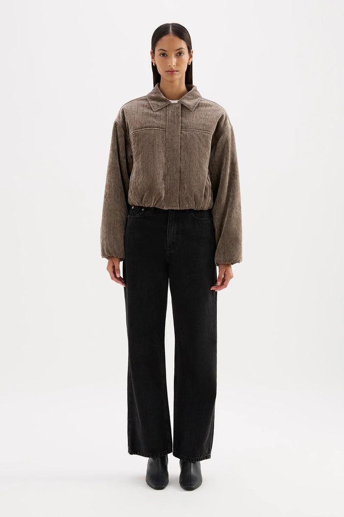 Woman wearing a brown jacket and black pants on a white background