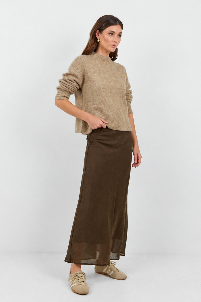 Woman wearing a beige sweater and brown skirt on a white background