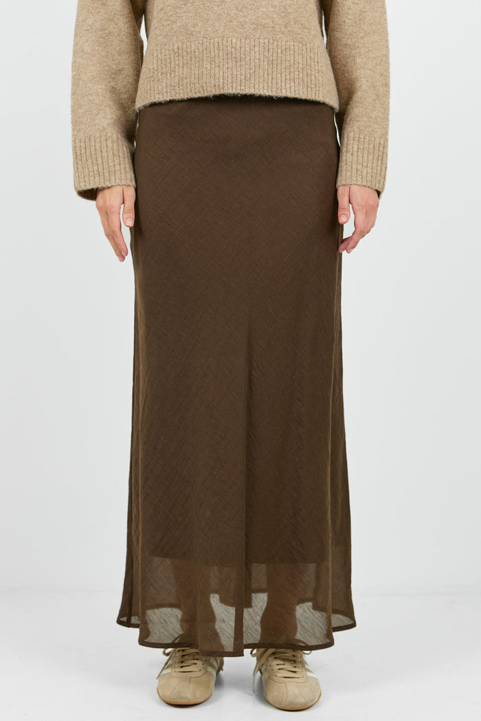Person wearing a beige sweater and brown skirt on a white background