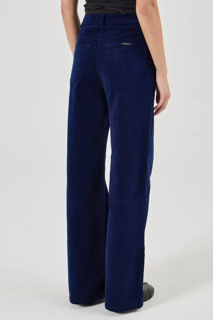 Navy blue corduroy pants worn by a person on a white background