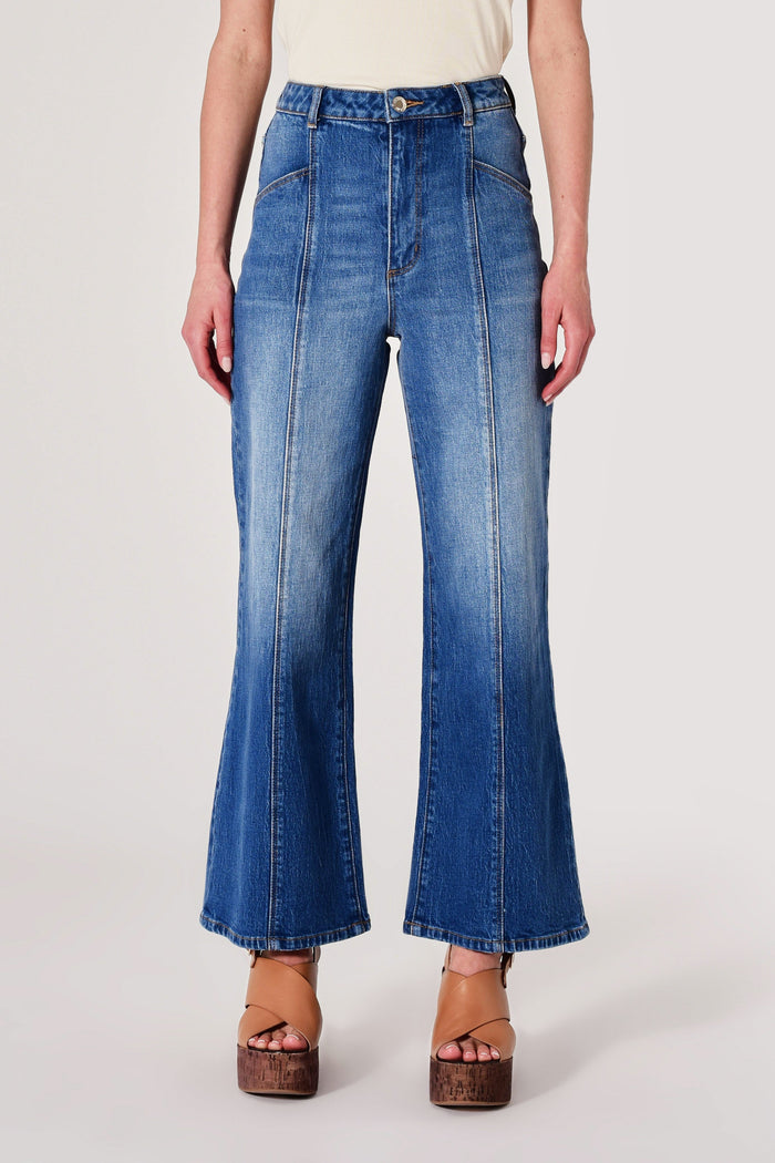 Person wearing blue flared jeans on a white background