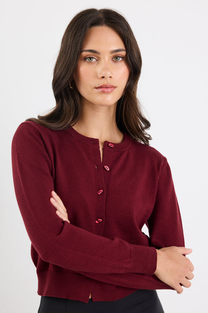 Woman wearing a burgundy cardigan with a plain background