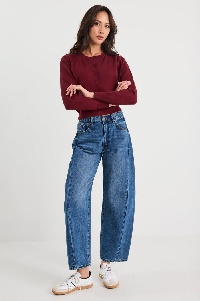 Woman wearing a burgundy sweater and blue jeans on a white background