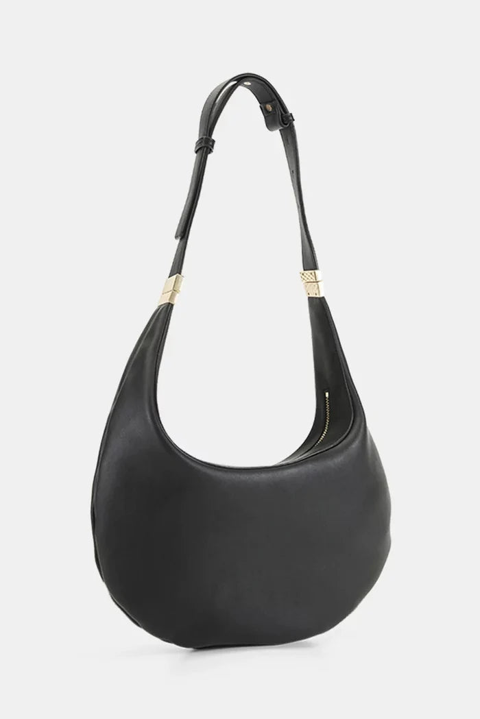 A black leather crescent-shaped shoulder bag with a single shoulder strap and gold-tone hardware, shown against a light gray background.