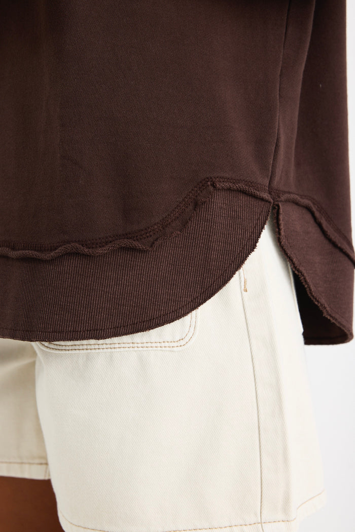 Relaxed-fit chocolate brown sweatshirt with tonal Re:Union embroidery, styled with cream shorts and gold hoop earrings.
col_pattern
