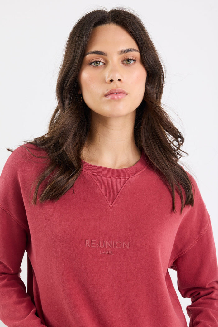 Woman wearing a red sweatshirt with 'Re:union' text on a white background