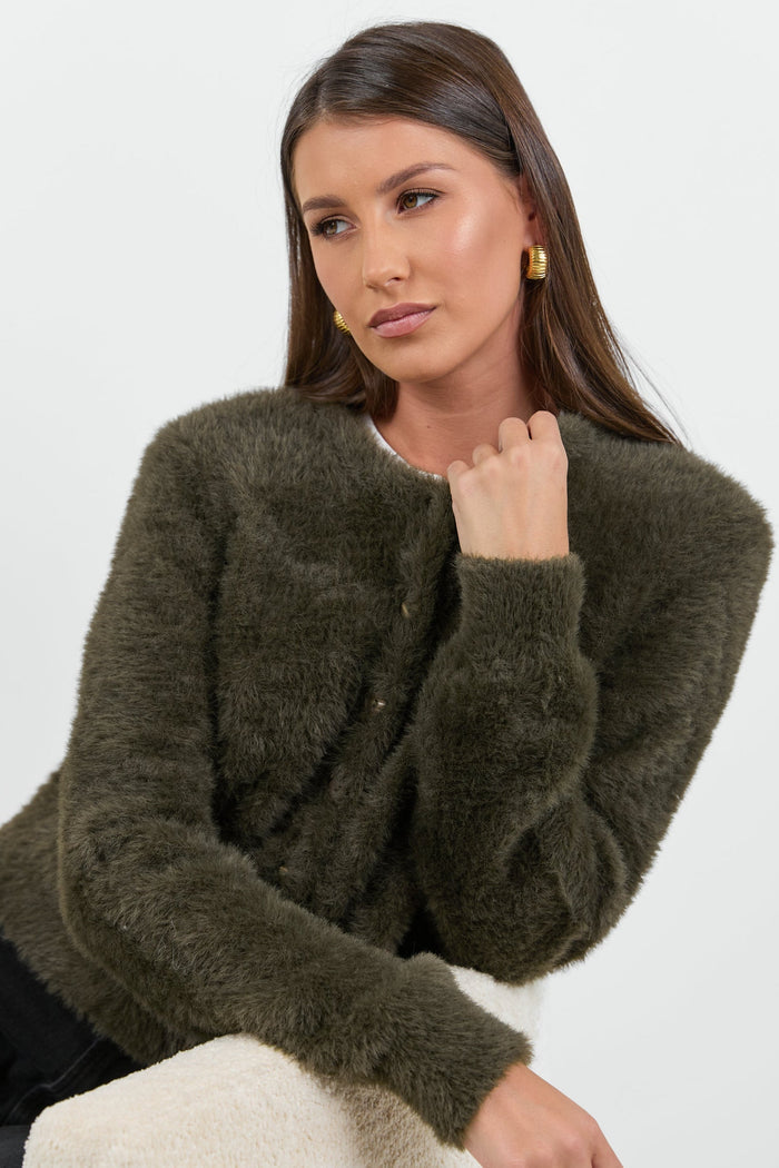 Woman wearing a green fuzzy sweater against a white background