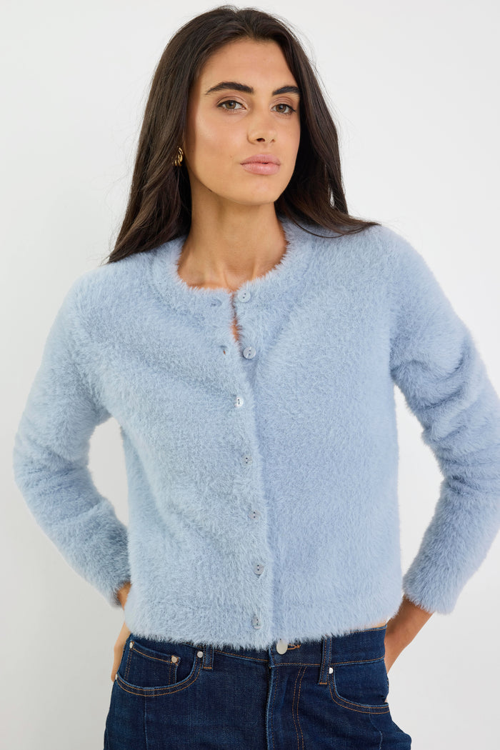 Woman wearing a light blue cardigan against a white background