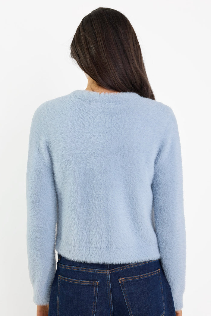 Person wearing a light blue sweater and dark jeans on a white background
col_pattern
