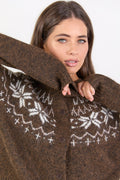 Woman wearing a brown knitted cardigan with white patterns on a plain background