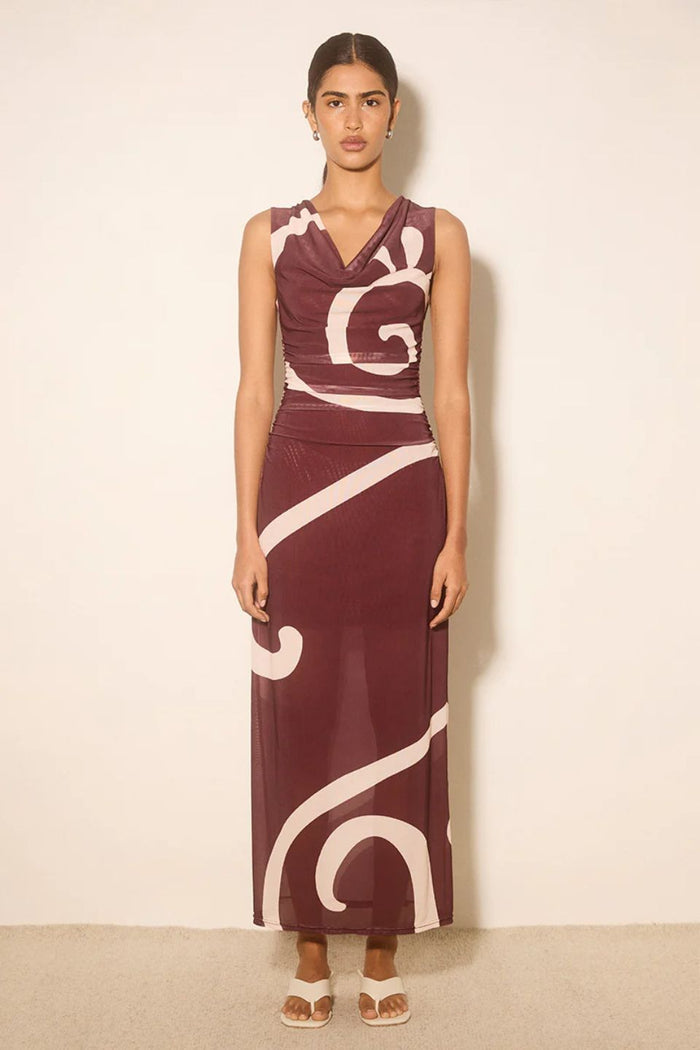 Woman wearing a burgundy dress with white abstract patterns on a beige background