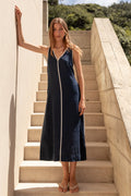 Woman in a navy dress standing on stone steps with a scenic background