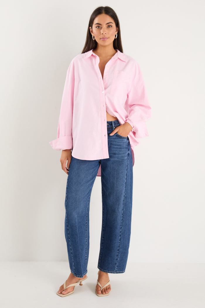 model wears a pink oversized shirt with blue jeans