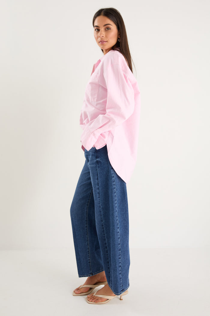 model wears a pink oversized shirt with blue jeans