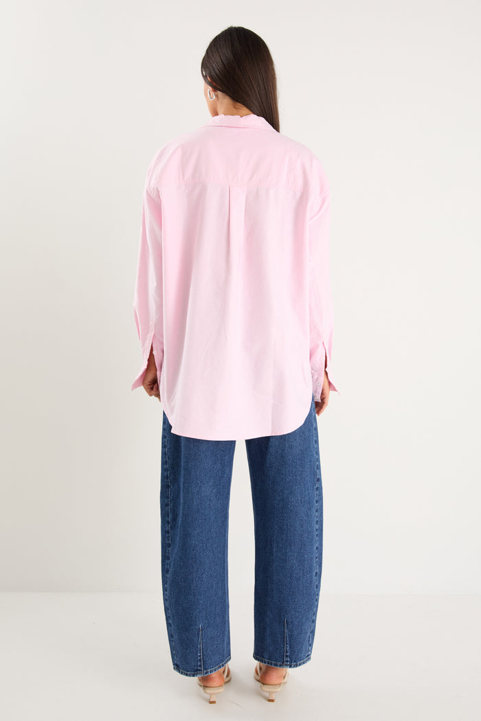 model wears a pink oversized shirt with blue jeans