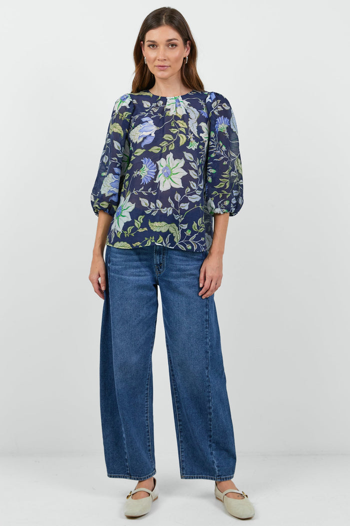Woman wearing a floral blouse and blue jeans on a white background