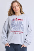 Woman wearing a gray sweatshirt with 'Aspen Foxwood Ski Club' text and graphics on a light gray background