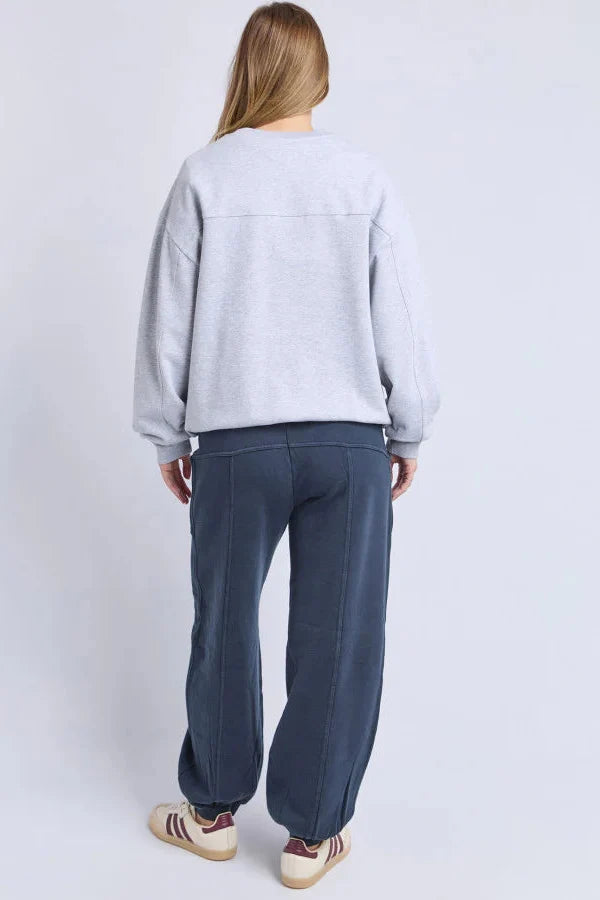 Person wearing a light gray sweatshirt and dark blue pants on a white background