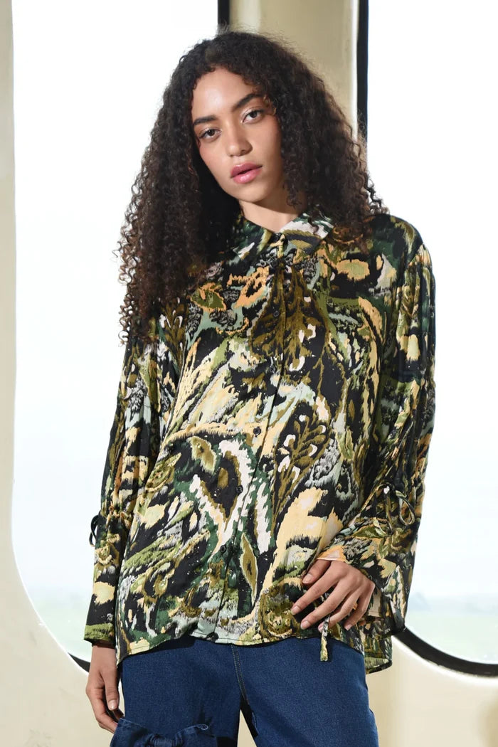 Woman wearing a patterned blouse with a blurred background