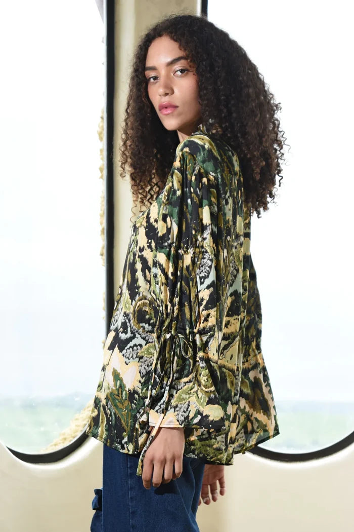 Woman wearing a patterned top with a scenic background