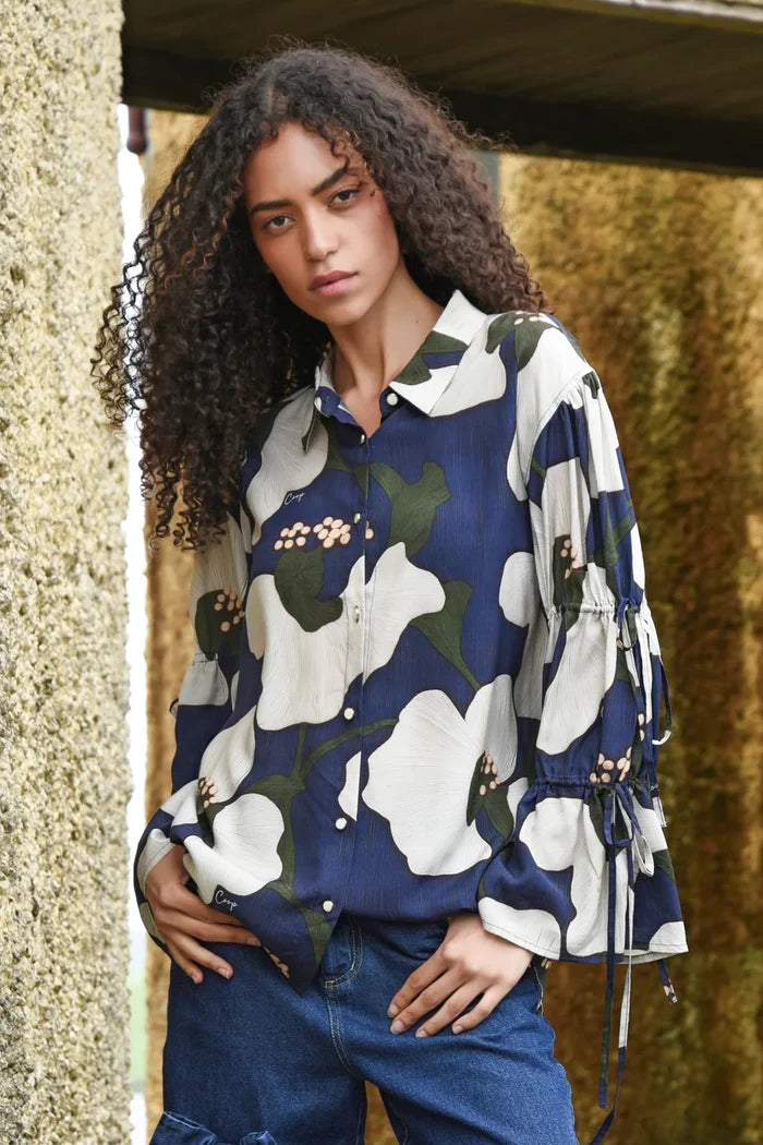 Woman wearing a floral patterned shirt with a blurred natural background