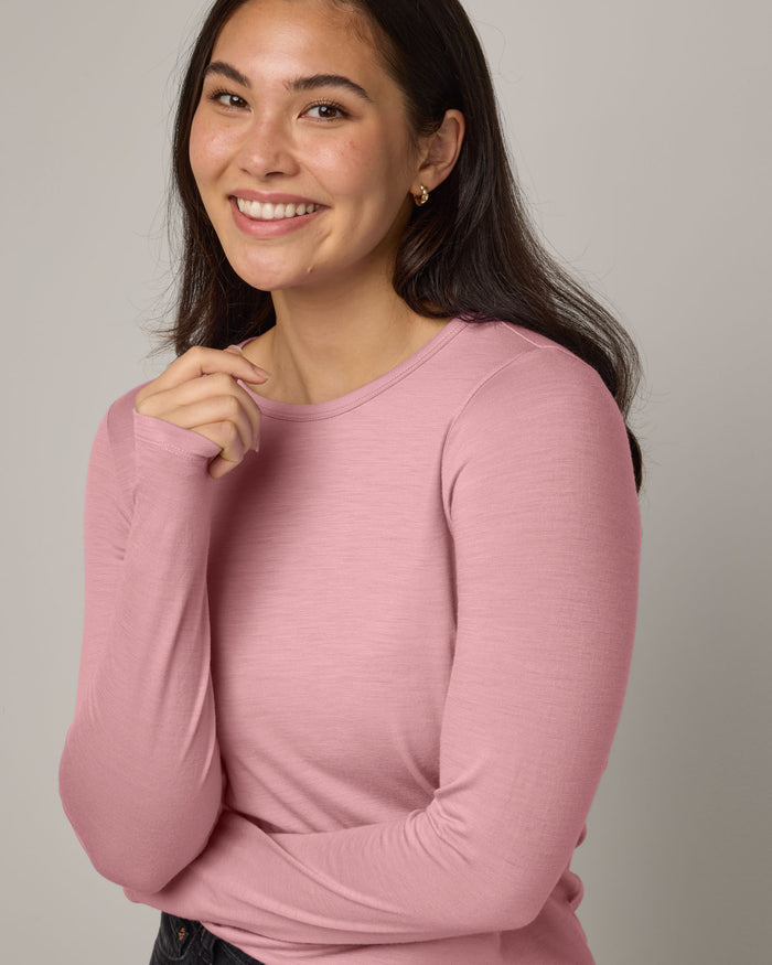 Model wearing Sloan 100% Fitted Tee in Ballet Pink, a baby light pink color. Sloan 100% Fitted Tee is a merino wool long sleeve, crew neck, slim fit tee available in sizes XS-3X.