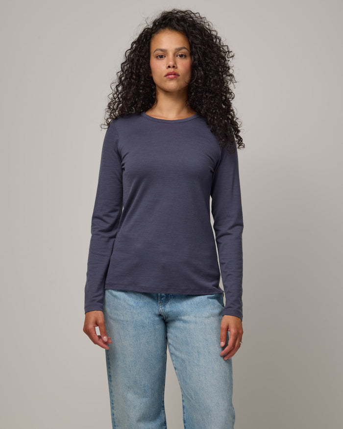 Model wearing Sloan 100% Fitted Tee in Odyssey Gray, a slate blue-gray color. Sloan 100% Fitted Tee is a merino wool long sleeve, crew neck, slim fit tee available in sizes XS-3X.