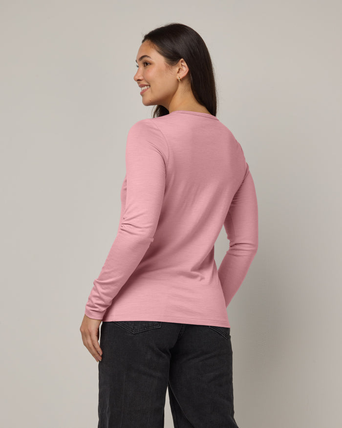 Model wearing Sloan 100% Fitted Tee in Ballet Pink, a baby light pink color. Sloan 100% Fitted Tee is a merino wool long sleeve, crew neck, slim fit tee available in sizes XS-3X.