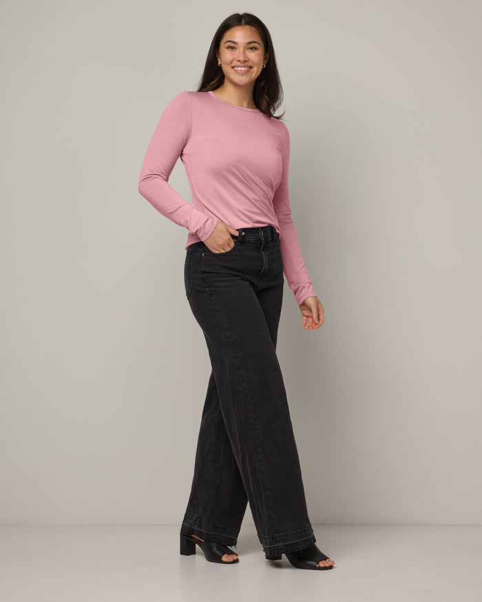 Model wearing Sloan 100% Fitted Tee in Ballet Pink, a baby light pink color. Sloan 100% Fitted Tee is a merino wool long sleeve, crew neck, slim fit tee available in sizes XS-3X.