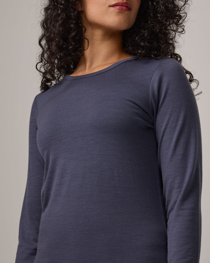 Model wearing Sloan 100% Fitted Tee in Odyssey Gray, a slate blue-gray color. Sloan 100% Fitted Tee is a merino wool long sleeve, crew neck, slim fit tee available in sizes XS-3X.