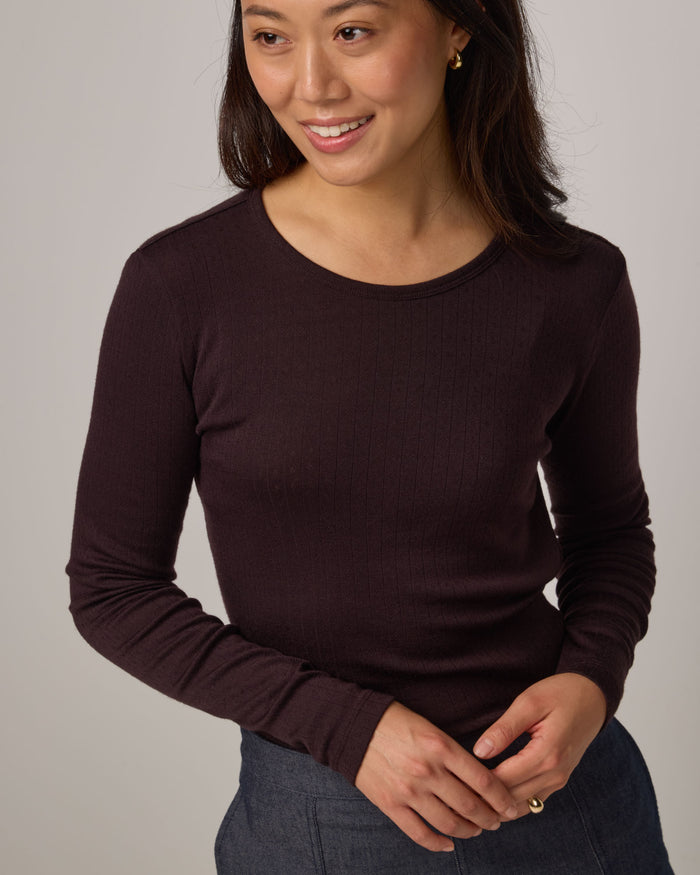 Model wearing Sloan Pointelle Fitted Tee in Espresso, a dark brown color. Sloan Pointelle Fitted Tee is a merino wool long sleeve, crew neck, slim fit tee available in sizes XS-3X.