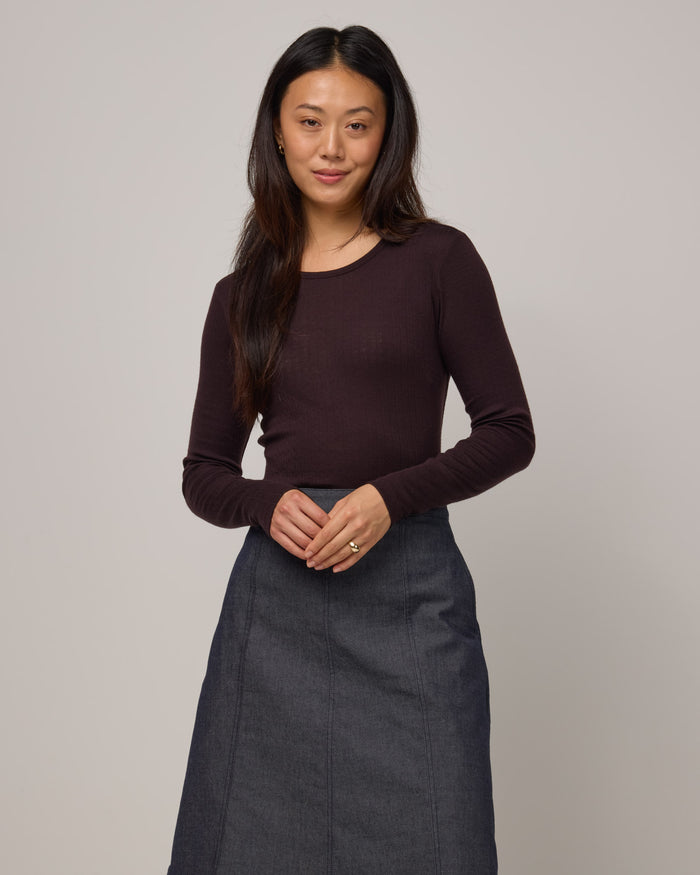 Model wearing Sloan Pointelle Fitted Tee in Espresso, a dark brown color. Sloan Pointelle Fitted Tee is a merino wool long sleeve, crew neck, slim fit tee available in sizes XS-3X.