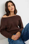 Woman wearing a brown sweater and blue jeans against a white background