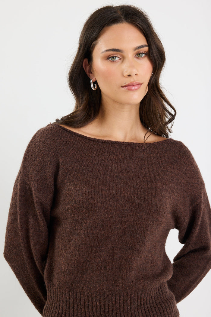 Woman wearing a brown sweater against a white background