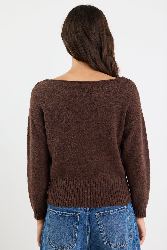 Person wearing a brown sweater and blue jeans on a white background