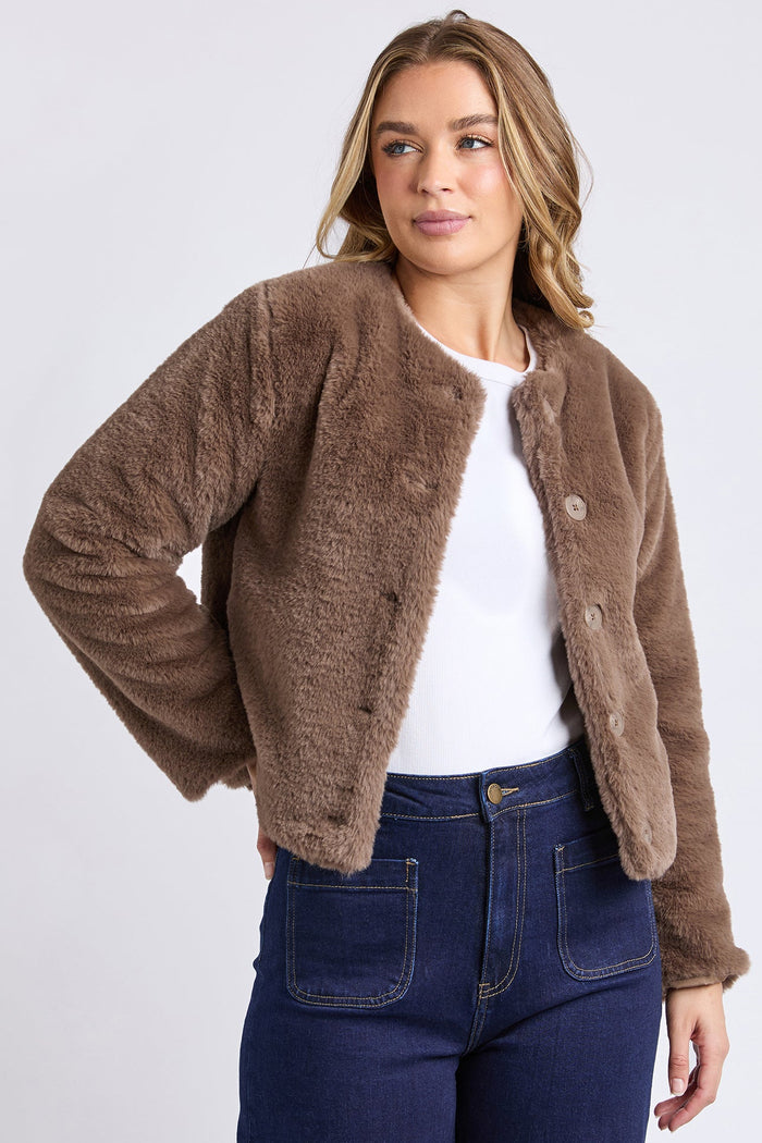Woman wearing a brown sherpa jacket and blue jeans on a white background