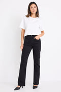 Woman wearing mid-rise, black wash jeans with a plain beige t-shirt and nude sandals.