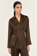 Woman wearing a brown blouse with a peplum waist on a white background