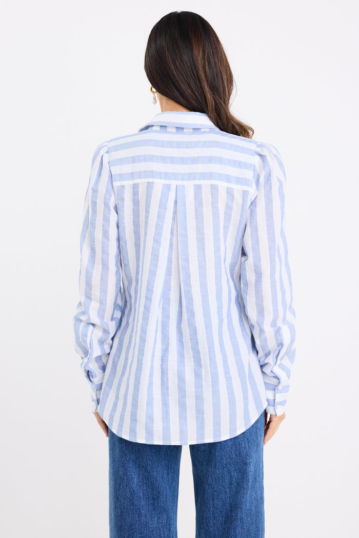 Woman wearing a relaxed blue and white vertical stripe shirt with balloon sleeves, styled casually with wide-leg blue jeans.
