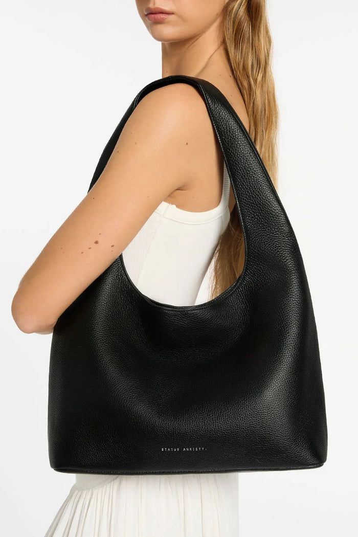 Person wearing a black leather handbag on a white background