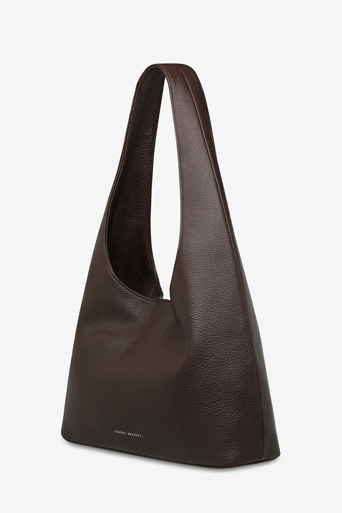 Brown leather handbag on a light gray background