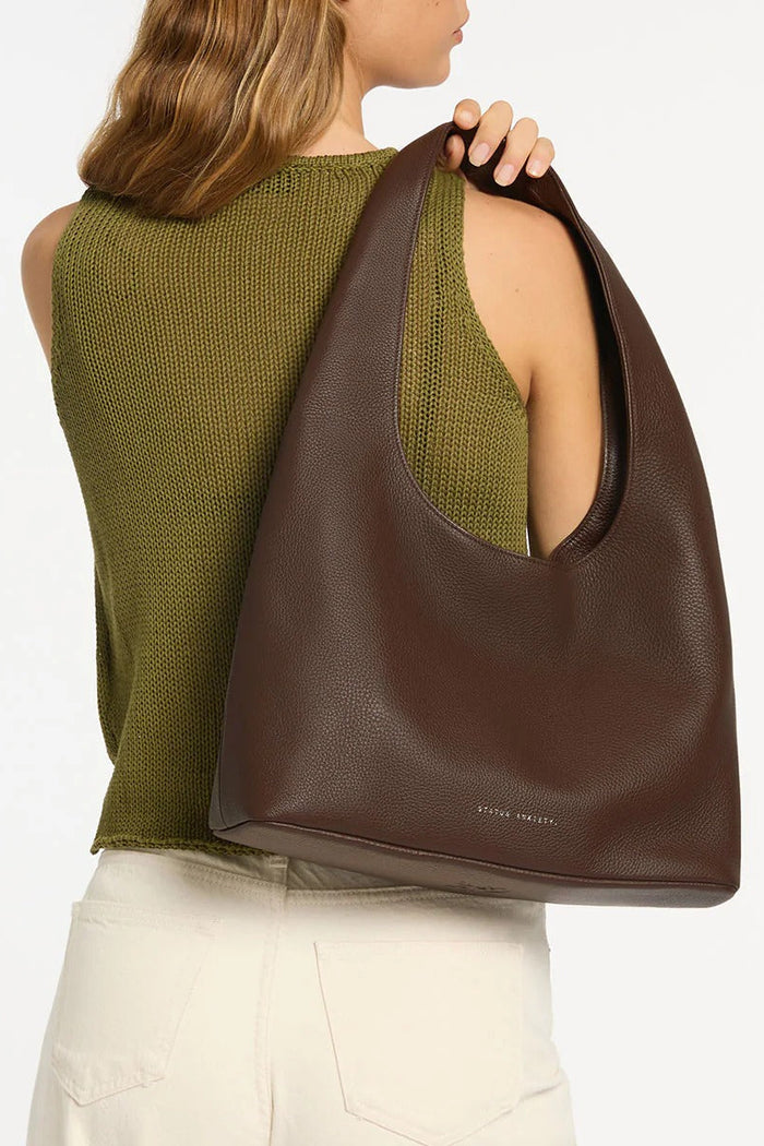 Woman carrying a brown leather bag on a white background