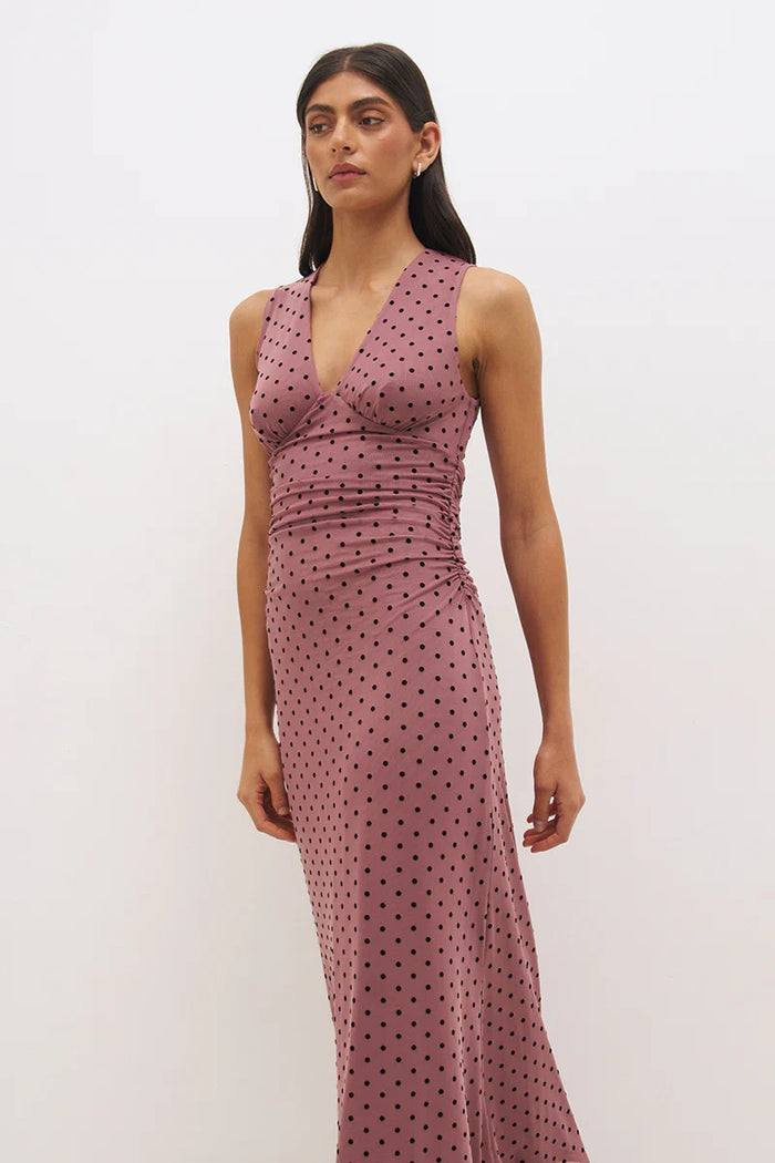 Woman wearing a pink polka dot dress against a white background