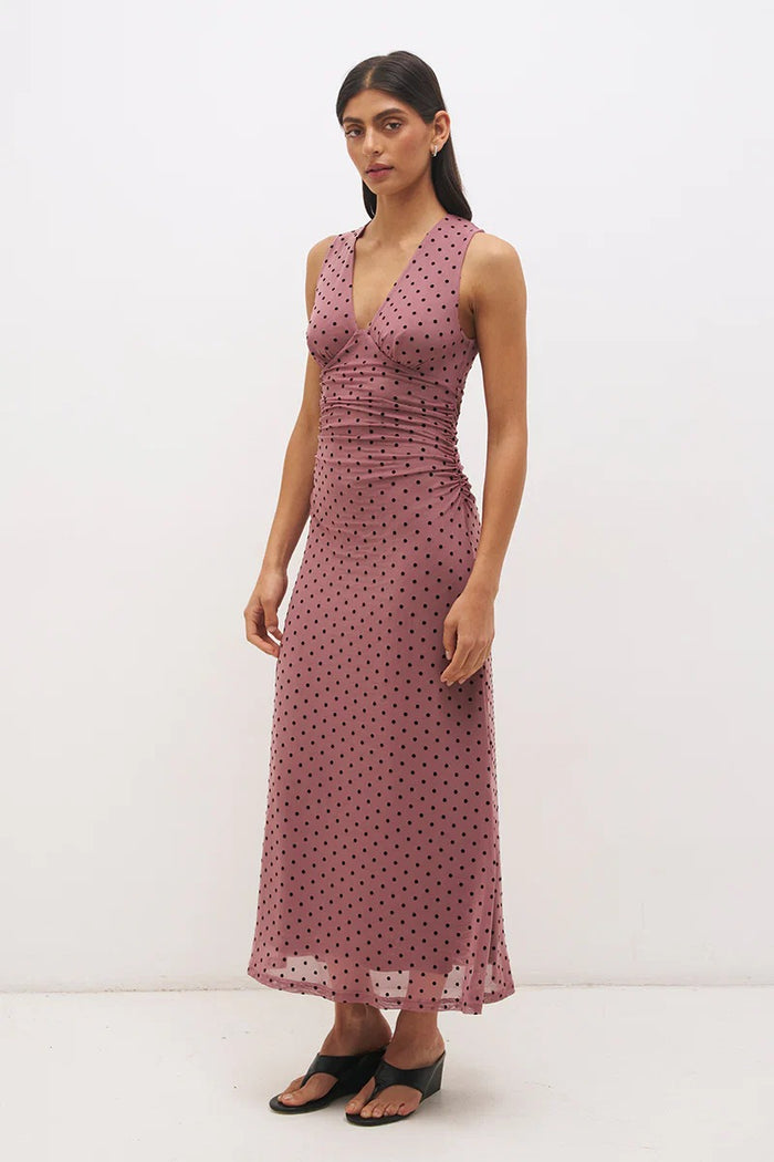 Woman wearing a pink polka dot dress against a white background