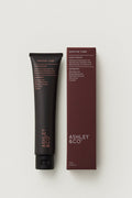 Black tube and maroon box of Ashley & Co hand cream on a light gray background