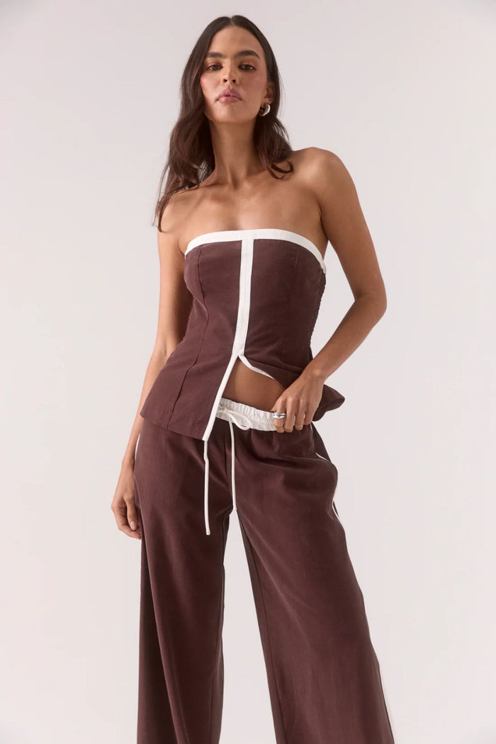 Woman wearing a brown and white strapless outfit on a white background