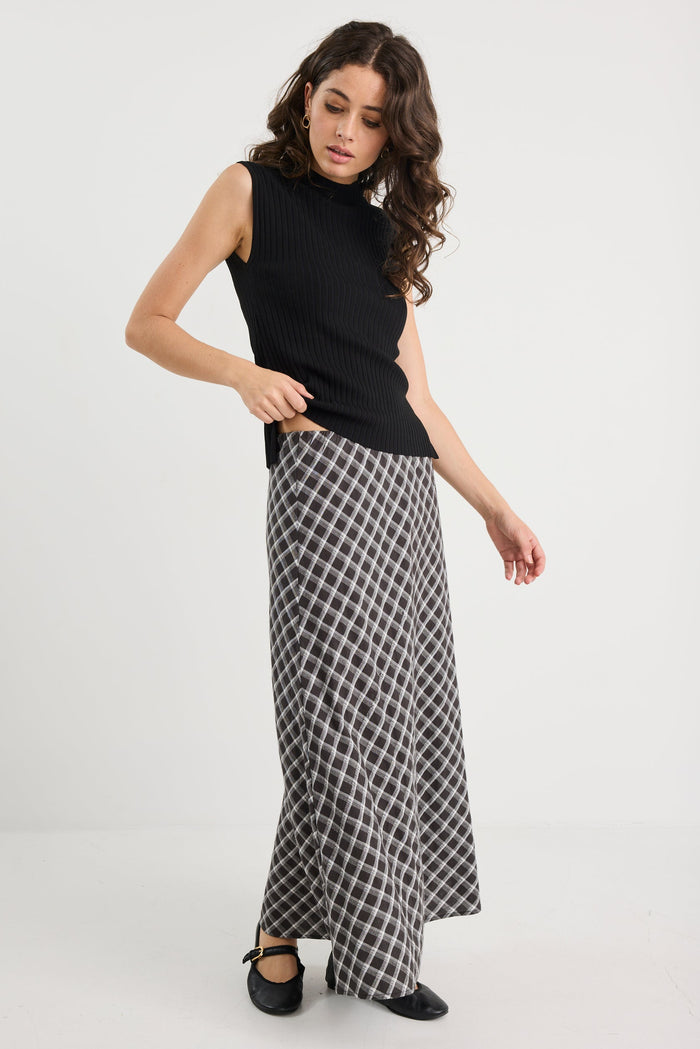 Woman wearing a black sleeveless top and checkered skirt on a white background