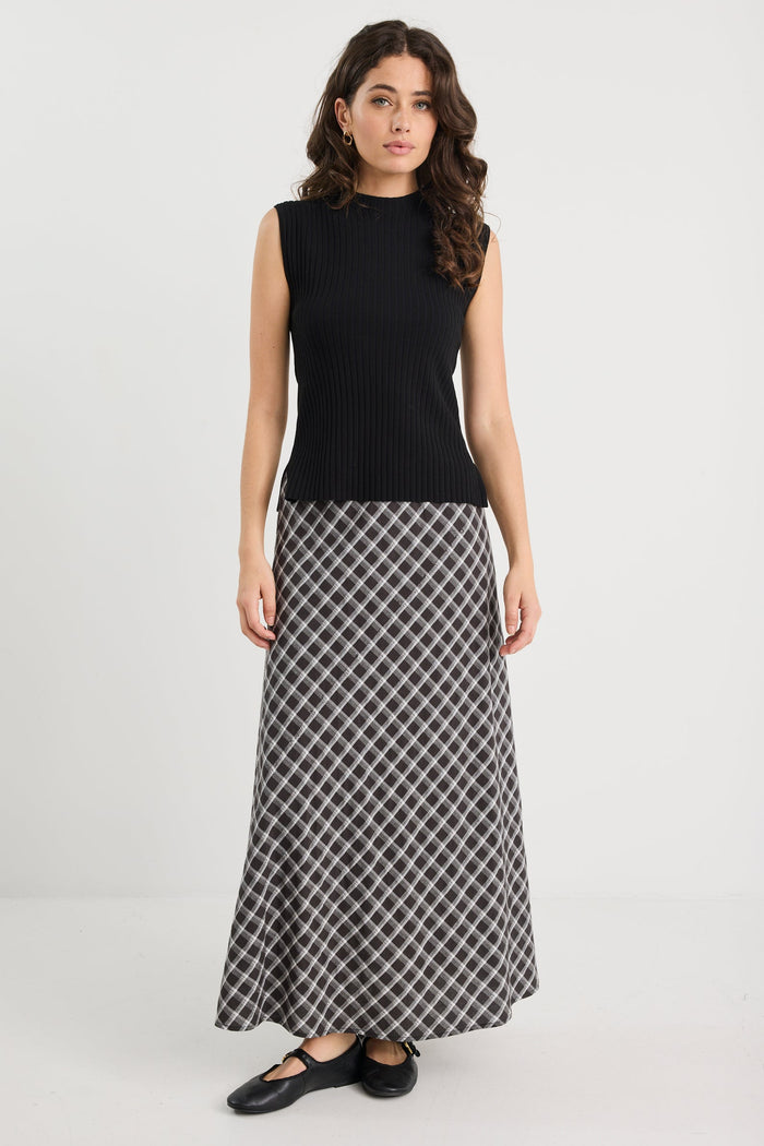 Woman wearing a black sleeveless top and patterned skirt on a white background