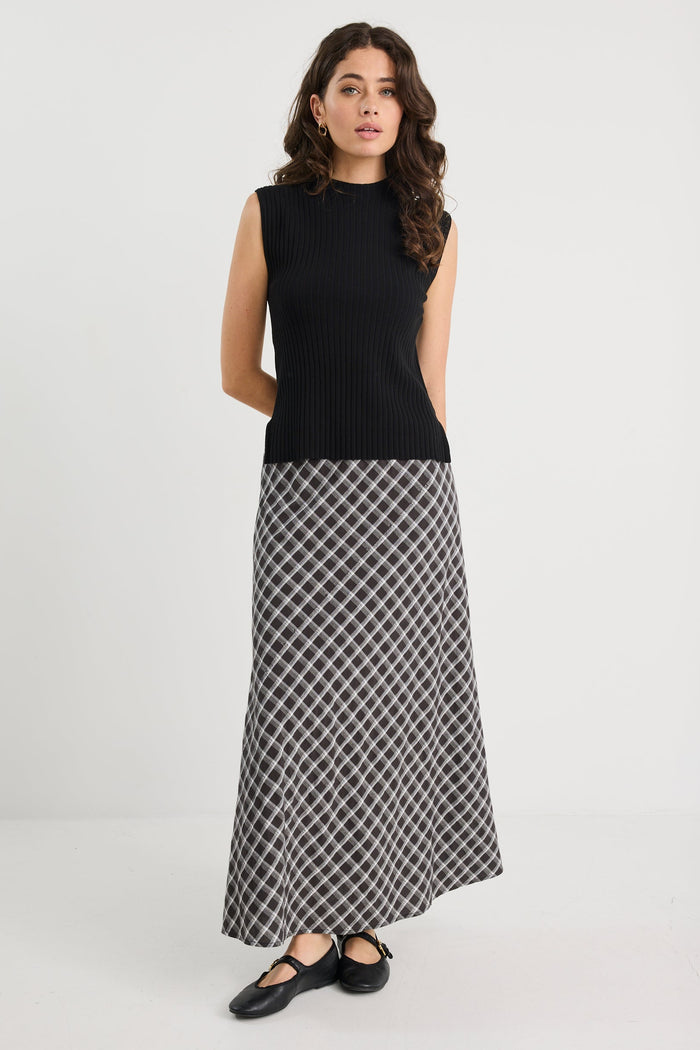 Woman wearing a black sleeveless top and patterned skirt on a white background