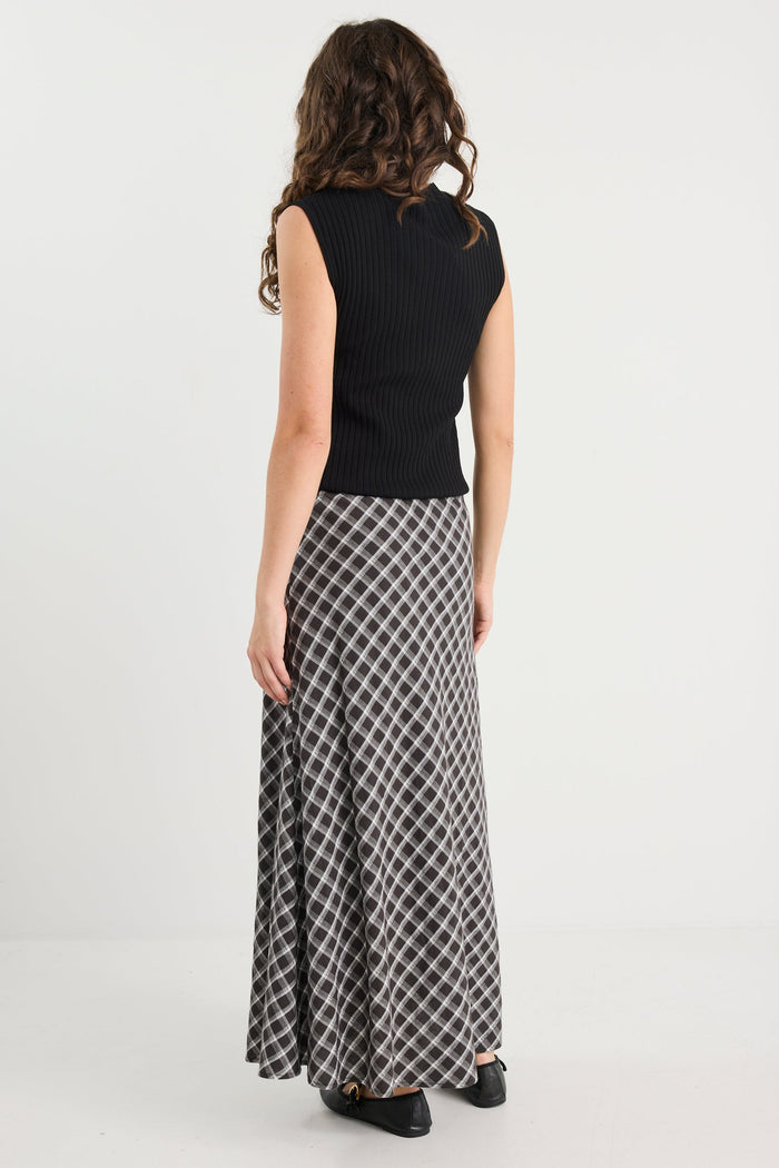 Woman wearing a black top and patterned skirt on a white background